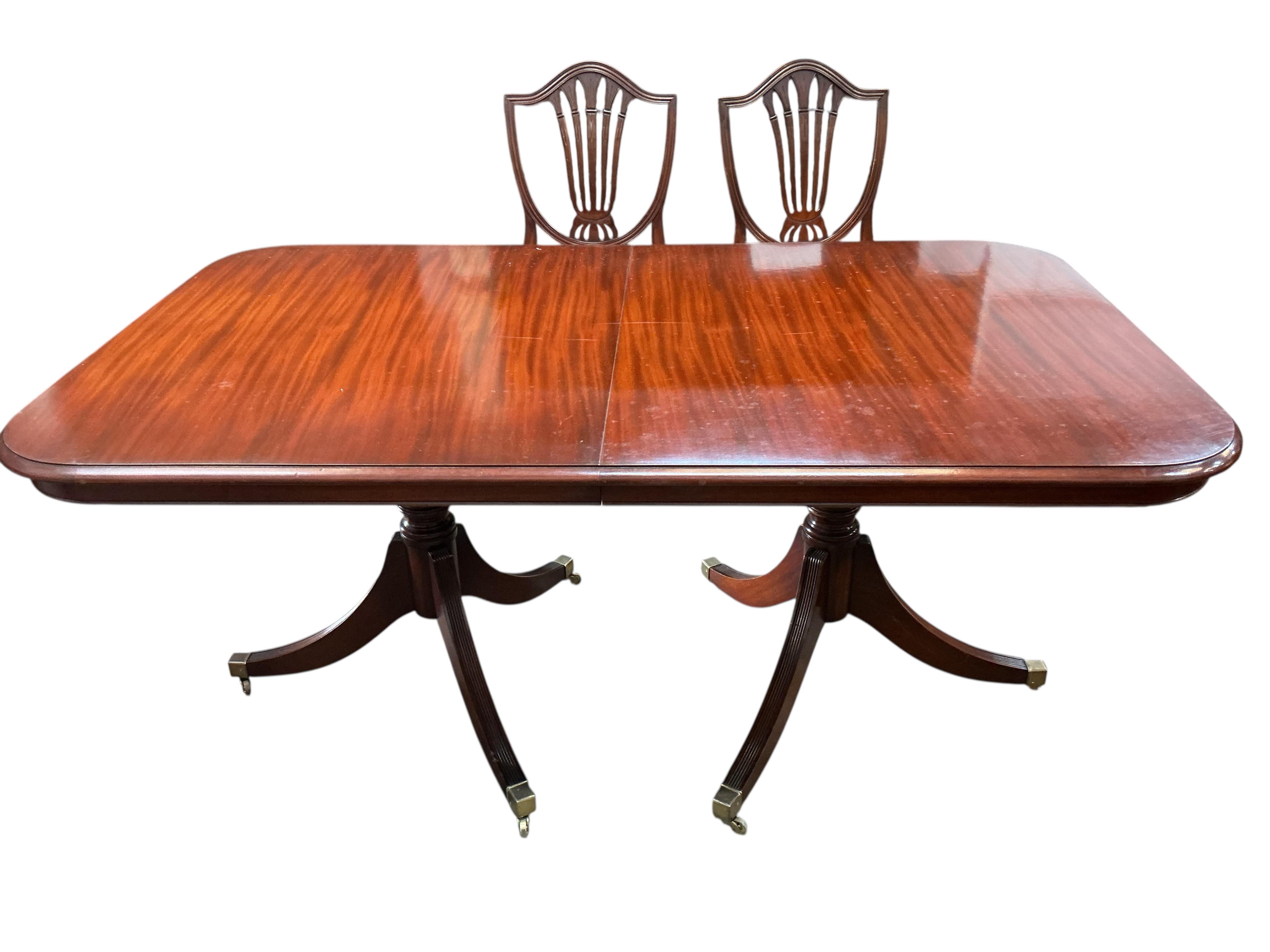 A reproduction mahogany twin pillar extending dining table, 216cm extended, one spare leaf, depth 98cm, height 74cm and eight Hepplewhite style dining chairs, two with arms